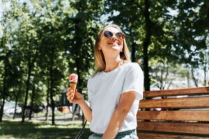 young woman sitting on park bench with ice cream