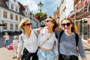 three young adults hugging and walking down the street happy